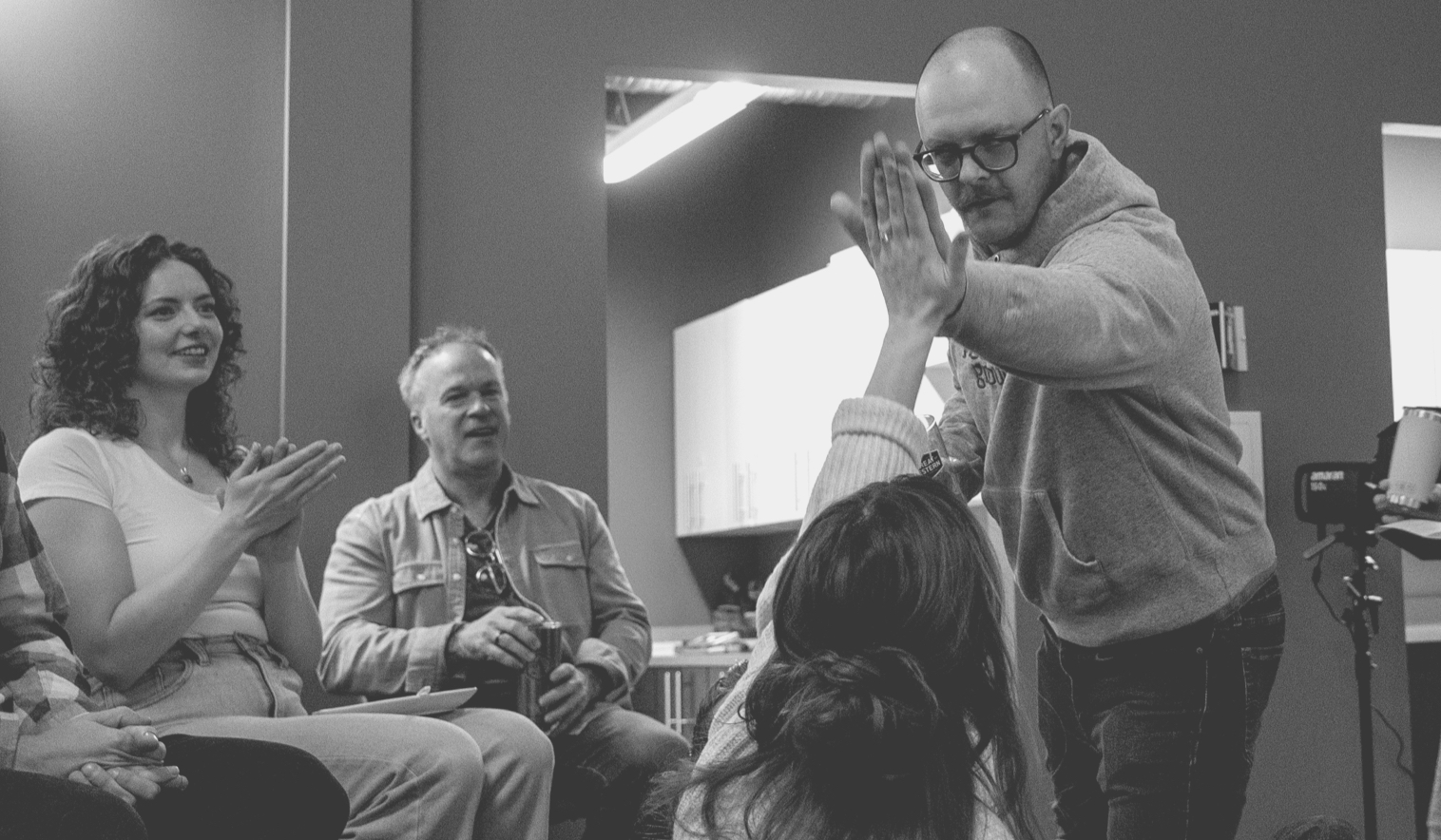 Two people highfiving in a conference room, with two more sitting in the crowd